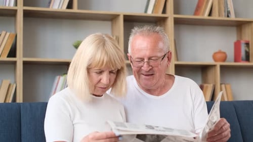 Aposentados italianos estão sentados em casa no sofá e lendo a última imprensa Happy Retired