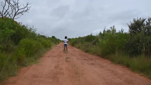 Ein kleiner Junge steht auf dem Weg einer unbefestigten Straße
