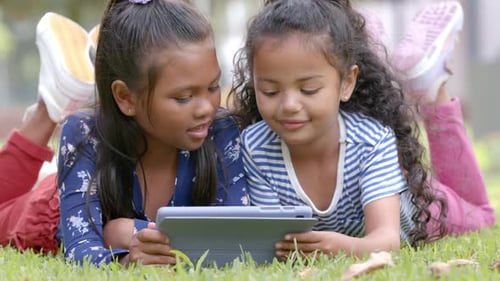 Girls Playing on Tablet Together in Green Grass