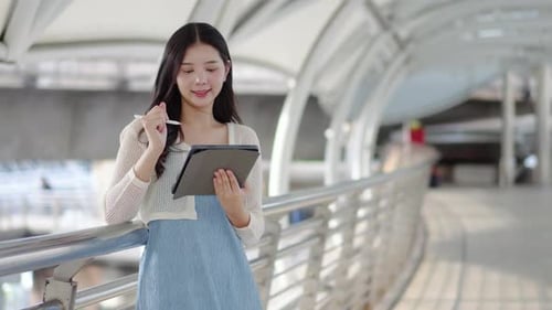 Young Woman Using Tablet on Modern City Walkway
