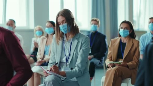 An Audience at a Business Conference Wears Masks for Safety Impacting Corporate Gatherings