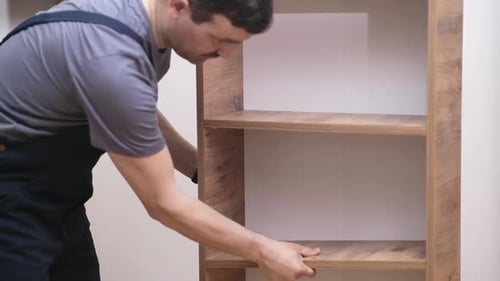 Adult Assembling Wooden Shelves in Home
