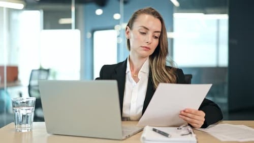 Professional Woman Reviews Documents at Her Office Desk