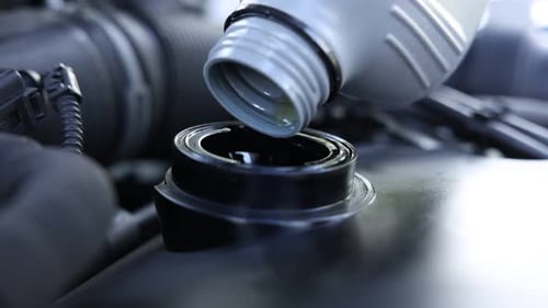 Motoröl aus der Flasche in den Automotor gießen, Nahaufnahme