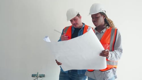 Team von Architekten oder Ingenieuren, die einen Schutzhelm tragen und nach einem Bauplan zur Inspektion suchen.