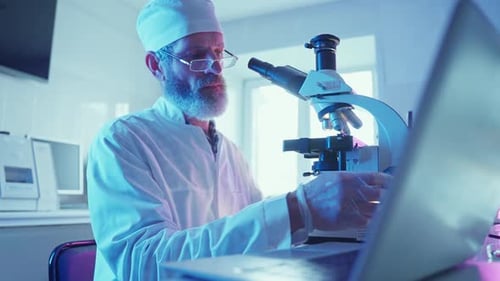 Scientist Uses Microscope and Computer in Lab