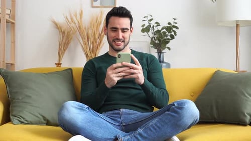 Man Relaxing on Couch Using Phone