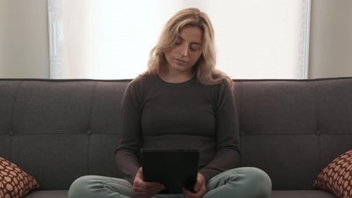 Woman Using Tablet on Couch in Bright Room