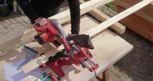Man cutting wood plank with power saw