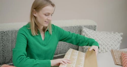 Woman Wrapping Gifts at Table Inside Home
