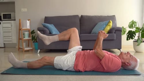 Senior Man Stretching Leg on Yoga Mat Indoors