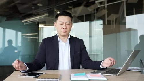Young Adult Meditating at Desk in Modern Office