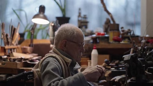 Senior Elderly Master Jeweler in Wheelchair Works in a Workshop