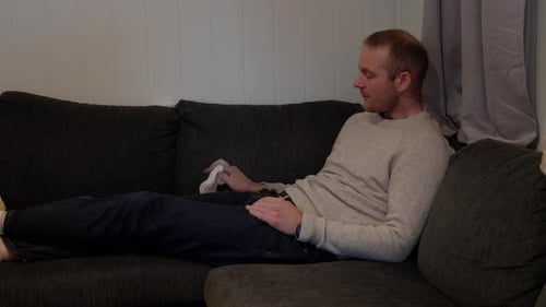 Sick Day, Man Coping with Cold and Flu Symptoms in Sofa Corner