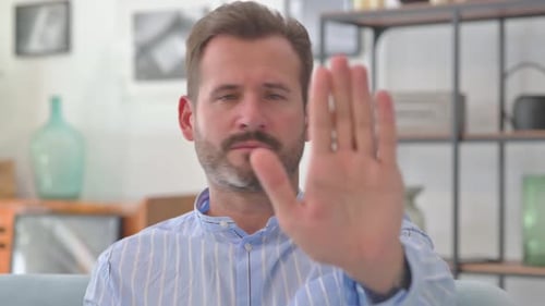 Portrait of Middle Aged Man with Stop Gesture Sitting at Home