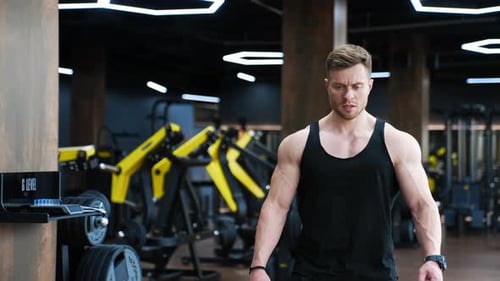 O
esportista cansado descansa após um treino intenso. Homem musculoso em camiseta preta em um moderno centro de fitness
.