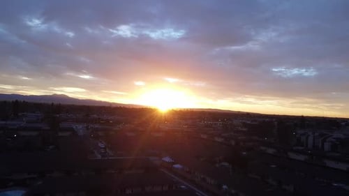 Sunrise through clouds over cityscape, drone shot.