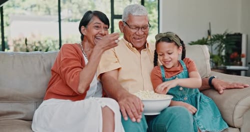 Movie, popcorn and family on sofa in home watching tv, cable or streaming funny movies in Mexico