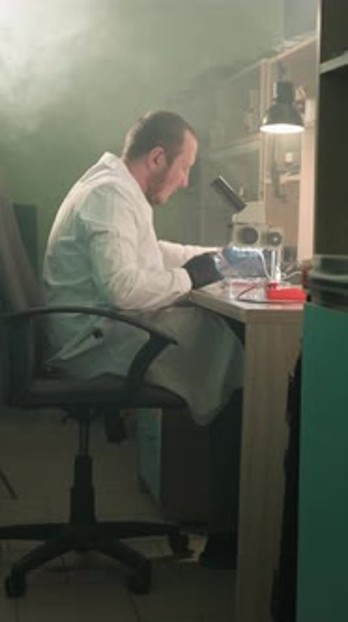Man Scientist Using Microscope in Smoky Laboratory