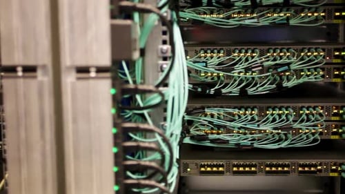 Green wires plugged in to servers and storage in a data center, server room