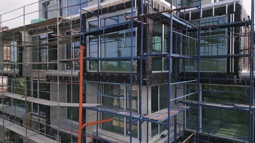Video of a Modern Building Under Construction with Blue Scaffolding Exterior Finishing Work in