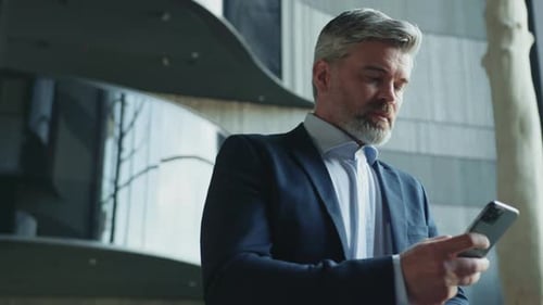 Man in Suit Using Phone in Modern Lobby