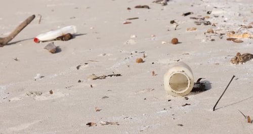 Littered beach with plastic waste scattered across the sand, highlighting environmental pollution