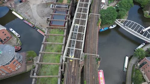 Vuelo aéreo con un dron sobre los muelles de Castlefield a vista de pájaro siguiendo un tranvía en un puente y solo
