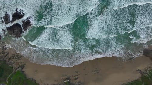Top Down View Over Ocean Waves With Foam Splashing On The Seashore - Drone Shot