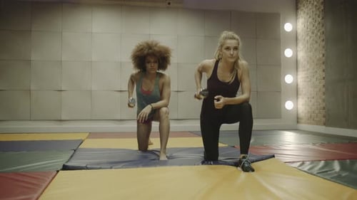 Two adult women exercising with weights in gym