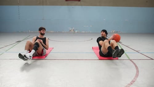 Two Athletes Warm Up With Basketball Inside A Gym