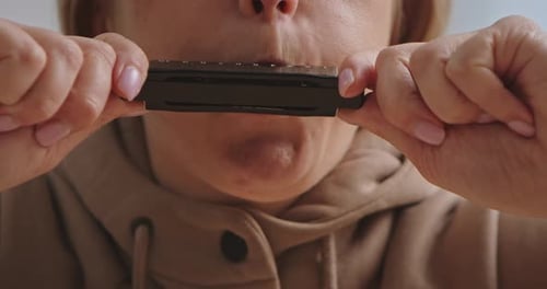 Close Up of Person Playing Harmonica with Focused Expression