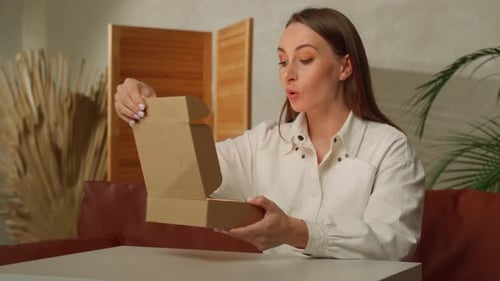 Woman Opens Box with a Smile Indoors