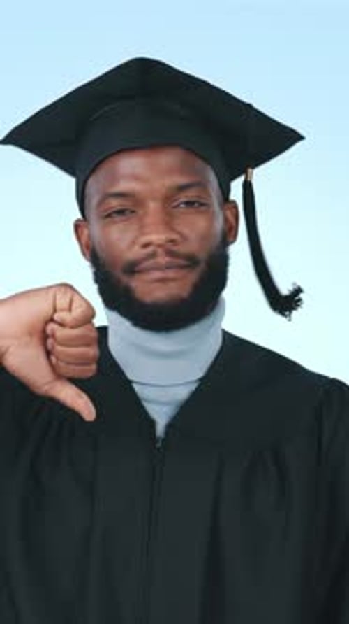 Face, student and thumbs down at graduation in studio for feedback, academic fail and poor decision