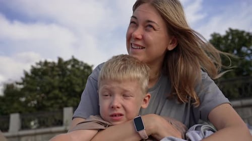 Madre consolando a su triste hijo con un tierno abrazo al aire libre