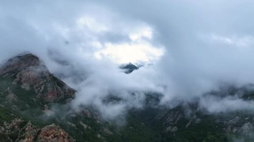 Misty mountain landscape with clouds rolling over peaks at dawn