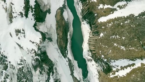 Aerial View of River Carving Through Snowy Canyon