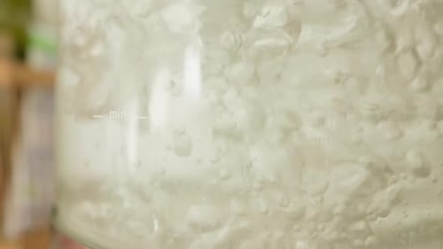 Boiling water close-up, vigorous bubbles in a clear kettle.
