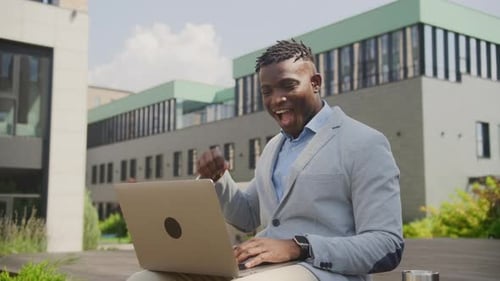 Successful Man Celebrates with Laptop Outdoors