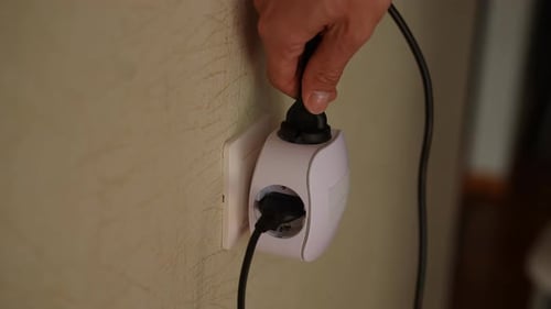 Hand Plugging Cord into Multi-Outlet Adapter