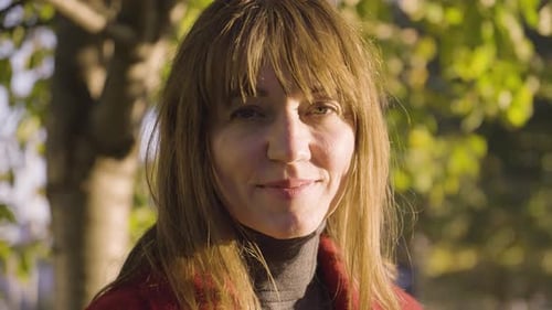 An Attractive Middleaged Caucasian Woman Smiles at the Camera in a Park Closeup