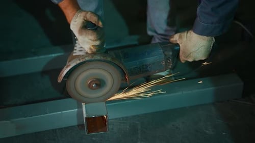 Metal Cutting Process Generates Sparks Scattering Across Entire Workshop Floor During Grinding