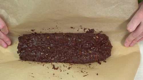 Hands Wrapping Chocolate Nut Dough in Parchment Paper