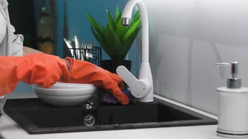 Woman Putting on Rubber Gloves to Wash Dishes