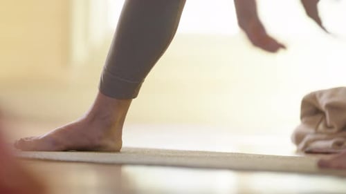 Low angle of feet as lady stretches down during yoga class in studio