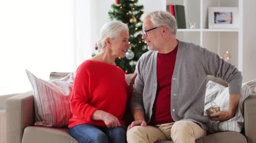 Loving senior couple exchanging Christmas gifts at home