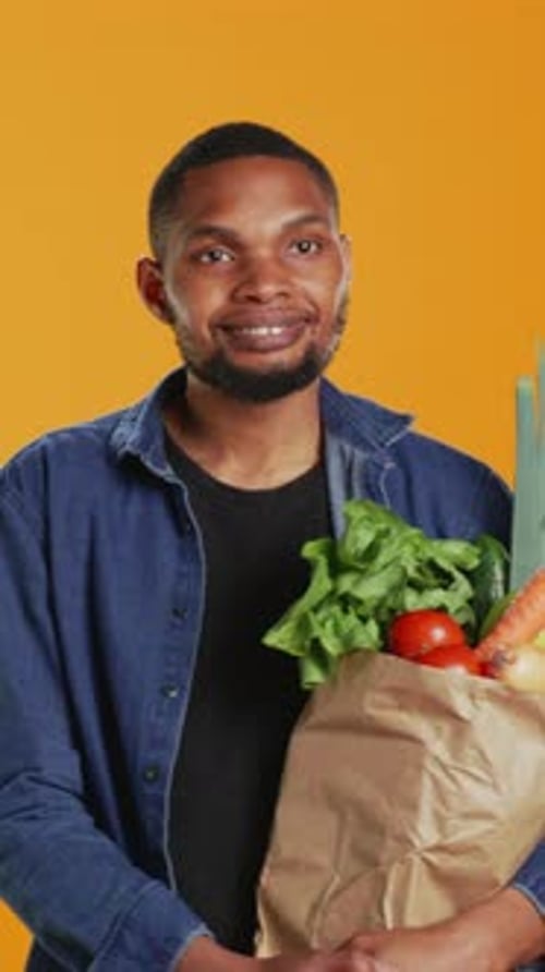 Smiling Young Adult with a Bag of Vegetables