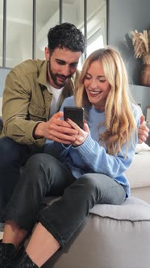 Smiling Couple Using a Smartphone Together at Home