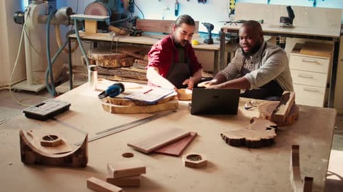 Two Woodworkers Collaborating on Design Using Laptop
