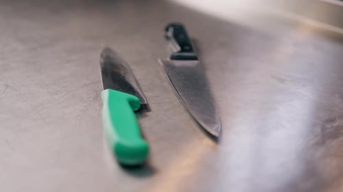Closeup of Large Slicing Knives Lying on a Metal Table in Professional Kitchen